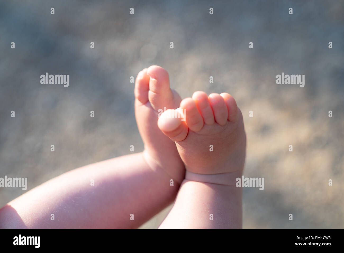 Bebé de 4 meses de edad sentado con los pies descalzos sobre una alfombra.  Juguetes en primer plano Fotografía de stock - Alamy