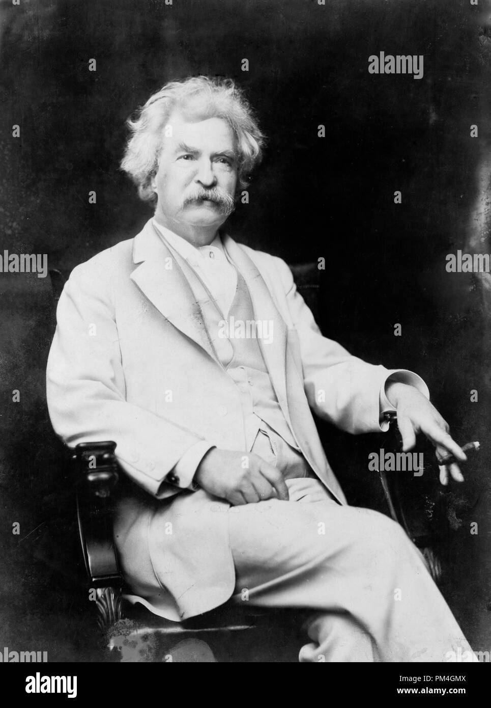 Mark Twain, tres cuartos de longitud vertical, sentado, mirando hacia la derecha, con cigarro en mano, circa 1907. Archivo de referencia # 1003 065tha Foto de stock