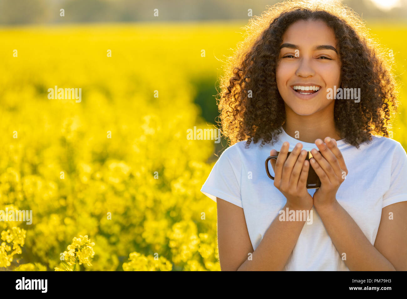 Feliz hermosa chica americana africana de raza mixta femenina adolescente joven sonriente bebiendo té o café al aire libre Foto de stock