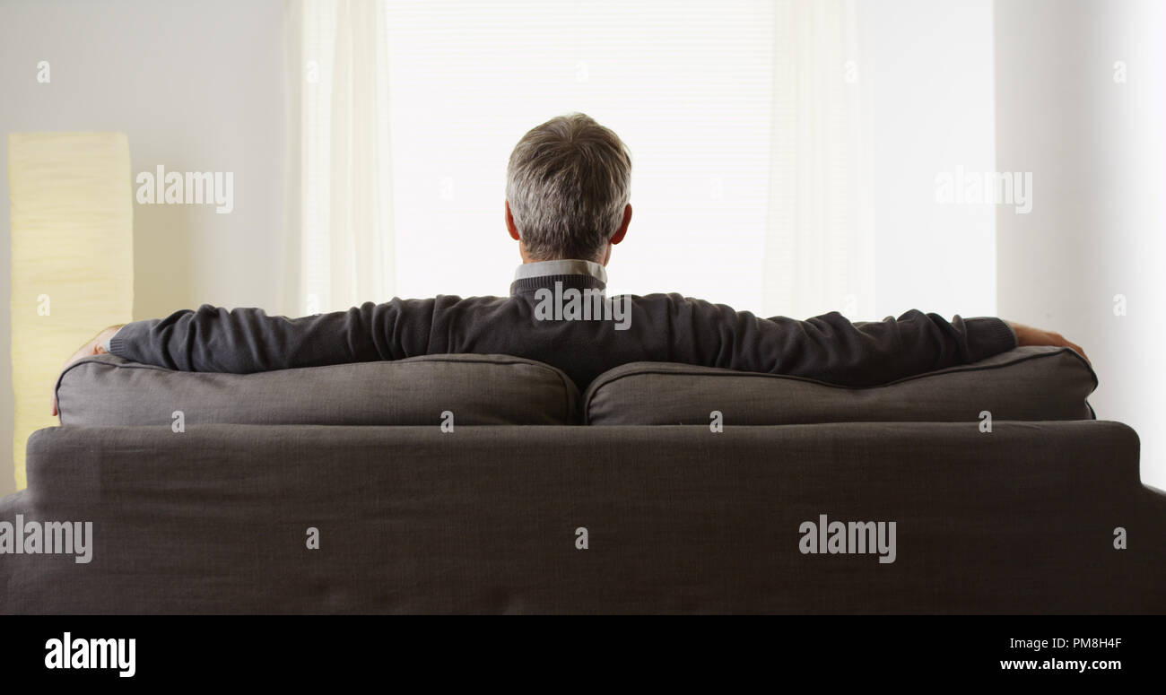 Pasivo hombre de mediana edad sentado en el sofá relajante Foto de stock