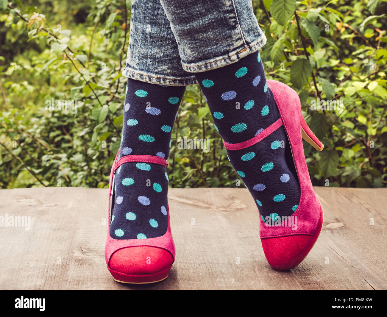 Las piernas las en zapatos elegantes, luminosas, abigarrado, multicolor calcetines en la terraza de madera sobre el telón de fondo de árboles. Estilo de vida, Moda, bea Fotografía de