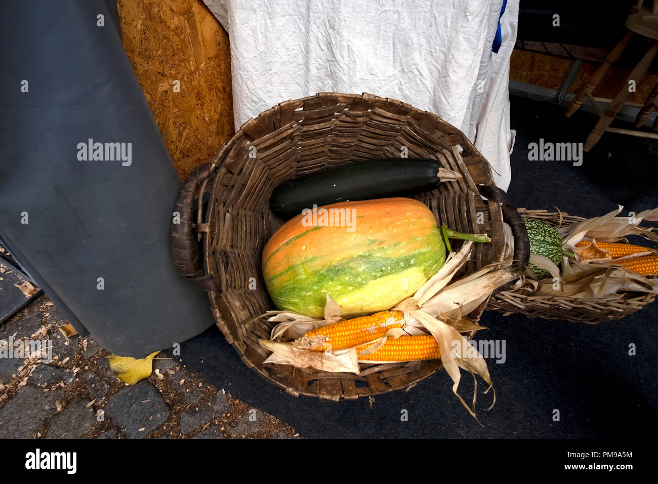 Cesta rústica sosteniendo una calabaza y maíz Foto de stock