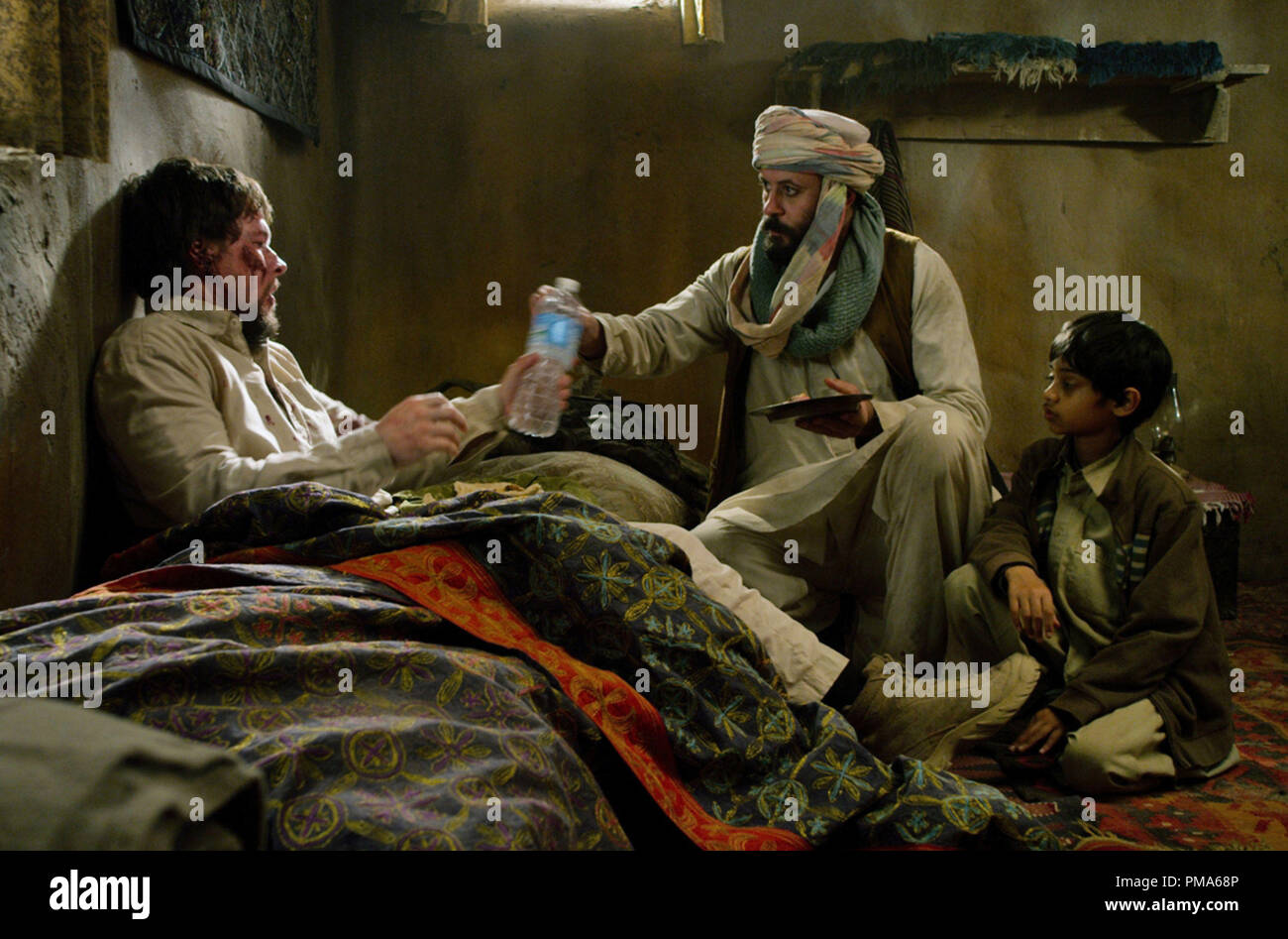 (L A R) Marcus Luttrell (Mark Wahlberg) es tratada por Gulab (ALI SULIMAN) y su joven hijo (ROHAN CHAND) en 'Lone Survivor' Foto de stock