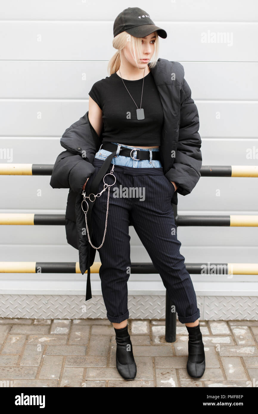 Moda elegante modelo negro moda mujer en una chaqueta de invierno con una  elegante tapa en pantalones jeans de moda posando cerca de una pared  metálica Fotografía de stock - Alamy