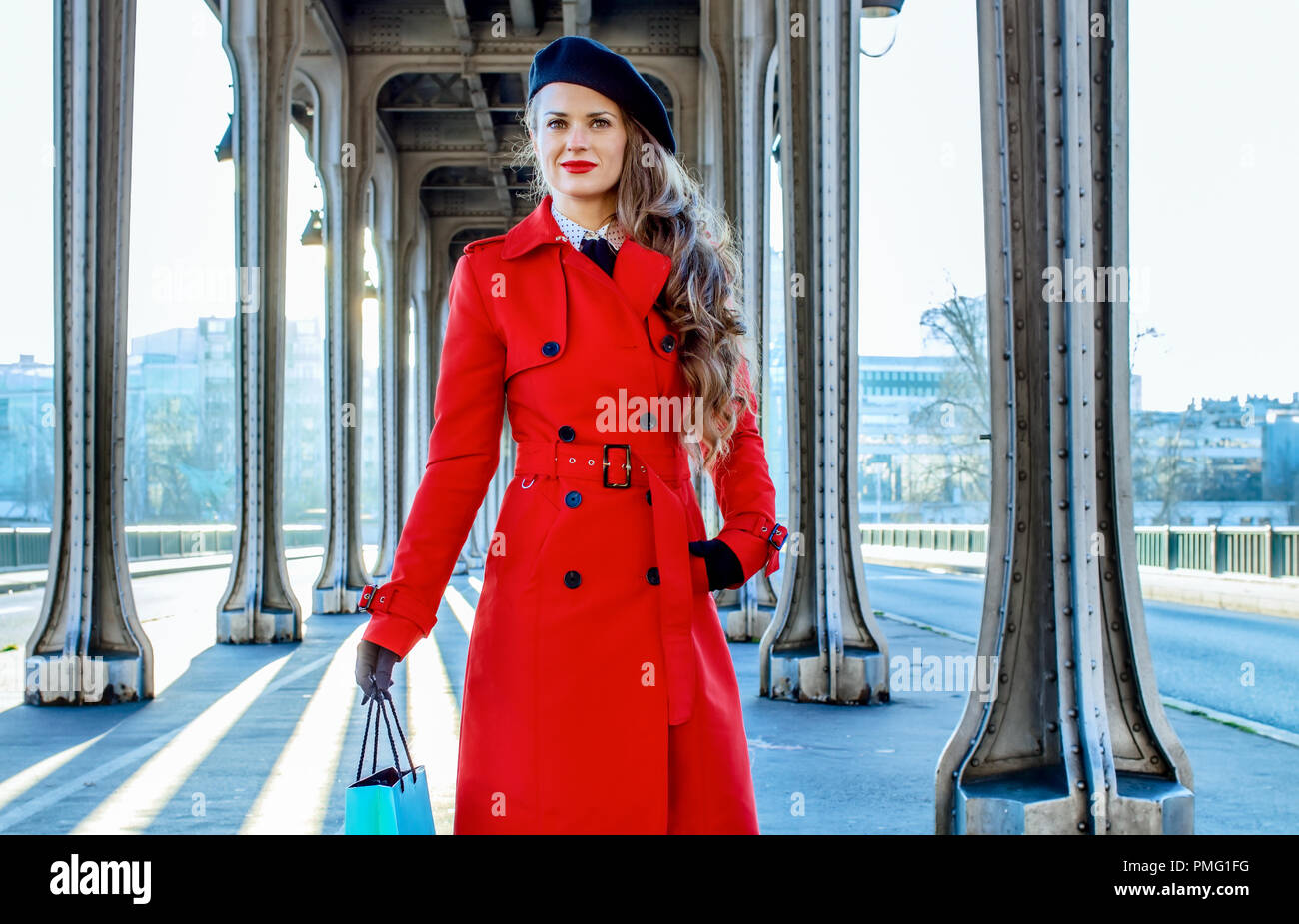 Brillante en París. joven viajero mujer de impermeable rojo sobre el puente  Pont de Bir-Hakeim en París con bolsa de compras Fotografía de stock - Alamy