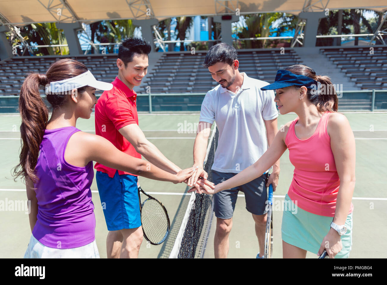 Cuatro jóvenes tenistas poniendo las manos juntas antes del match mixtos dobles Foto de stock