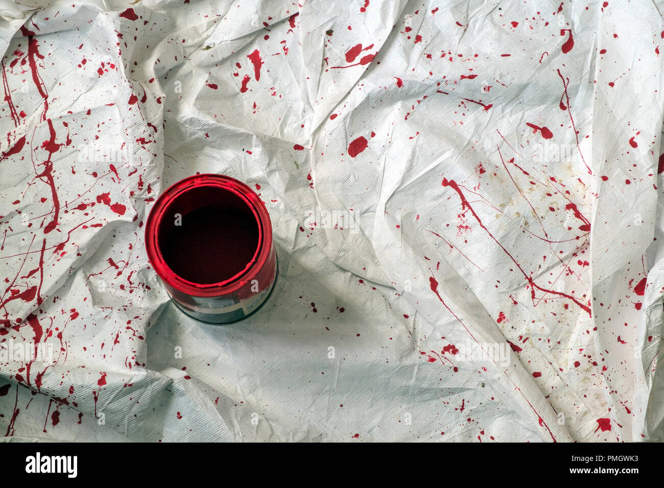 Un equipo de decoradores antipolvo con salpican de vibrante pintura roja alrededor de una lata de pintura abierta. Foto de stock