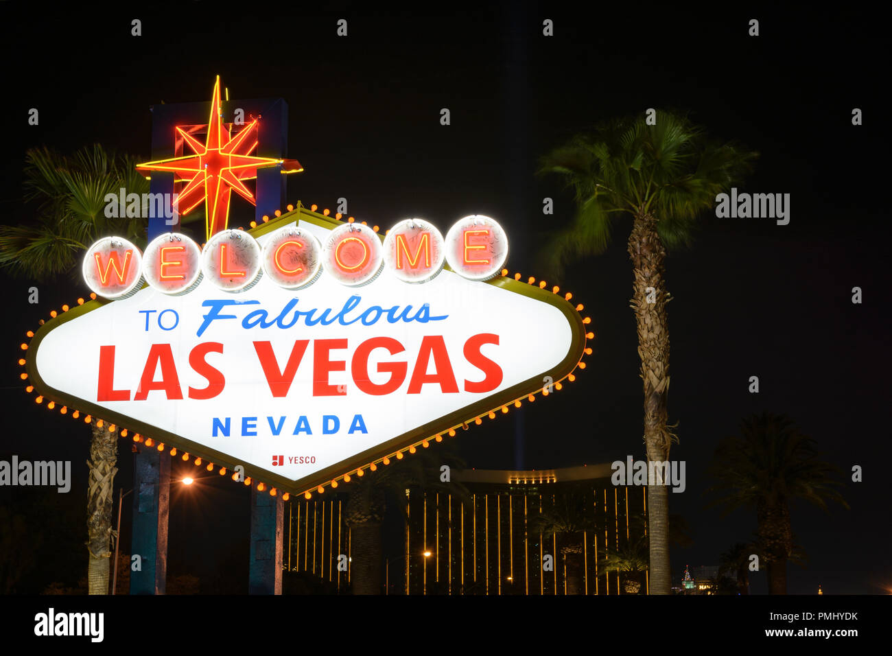 El Bienvenido a Las Vegas firmar por la noche con palmeras en el fondo Foto de stock