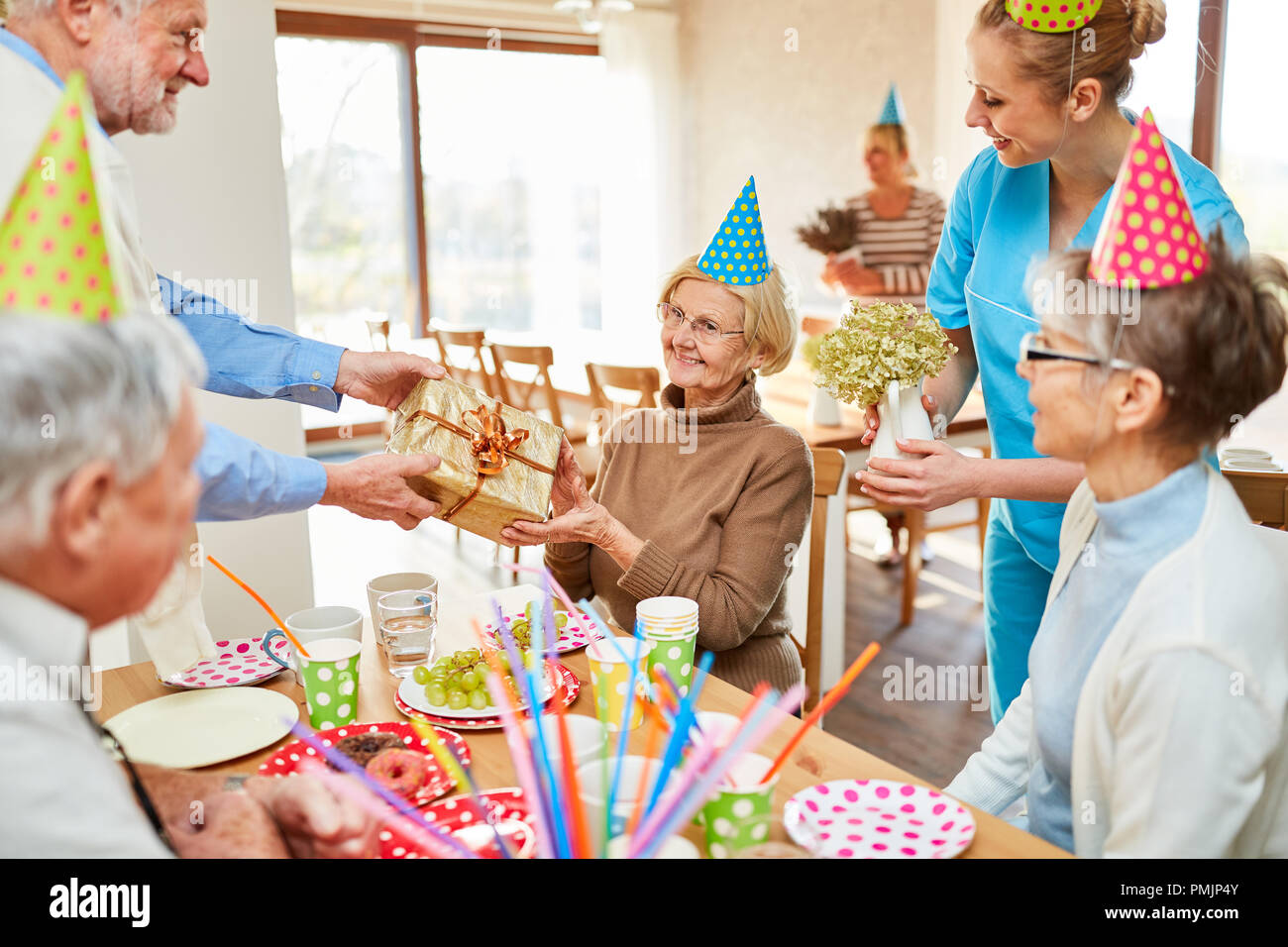 Mujer Senior recibe un regalo presentado en su fiesta de cumpleaños en la casa de retiro Foto de stock