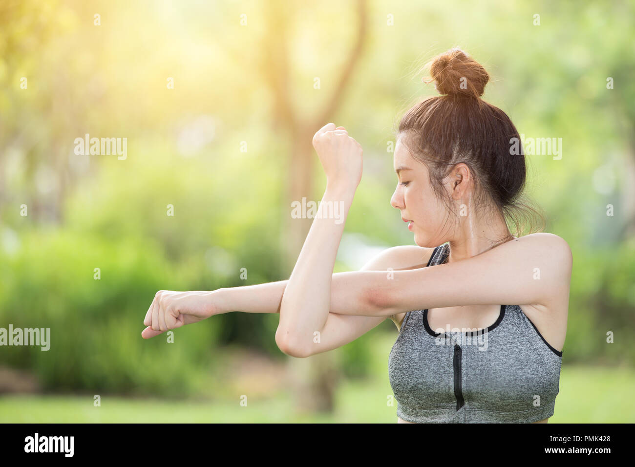 Lindo adolescente estirando el brazo hermosa niña en el parque el ejercicio al aire libre Foto de stock
