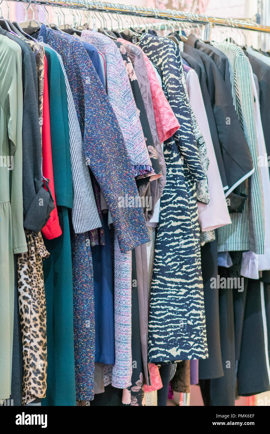 Coloridos vestidos de mujer en soportes en una tienda minorista. Concepto  de moda y compras. El colgador de ropa en la tienda de fotografía vertical  Fotografía de stock - Alamy