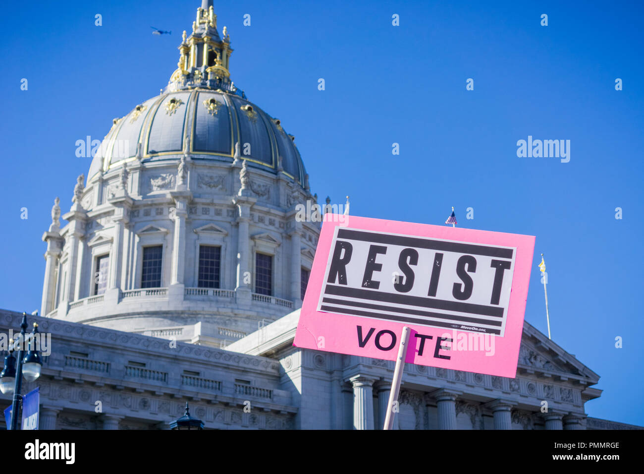 "Resistir Voto" signo planteadas en la mujer de marzo rally, Civic Center Plaza, San Francisco, California; el edificio del Ayuntamiento en el fondo. Foto de stock