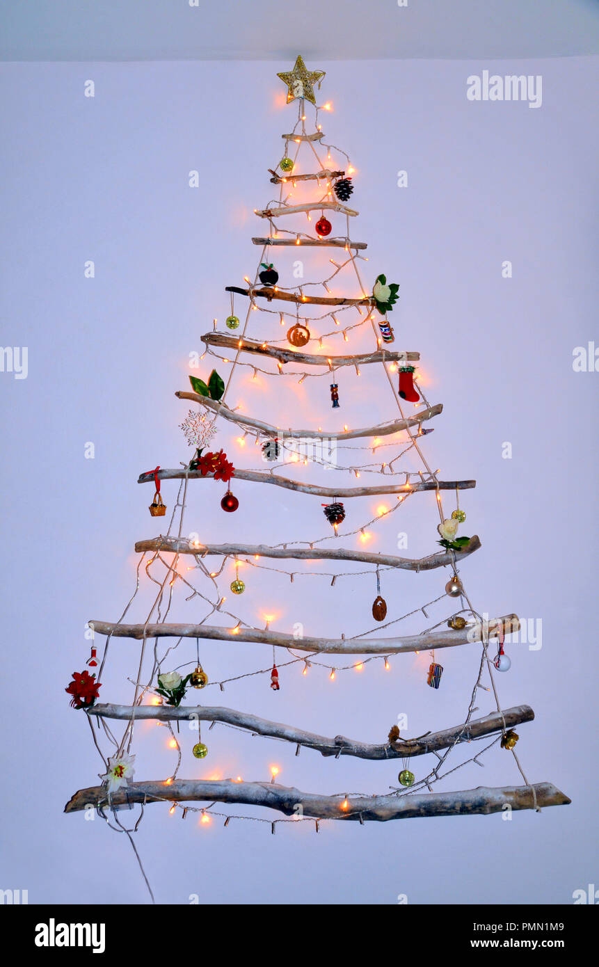 Su moderno y creativo para colgar en la pared hechas de troncos de árbol de  Navidad con luces y adornos colgantes y chucherías Fotografía de stock -  Alamy