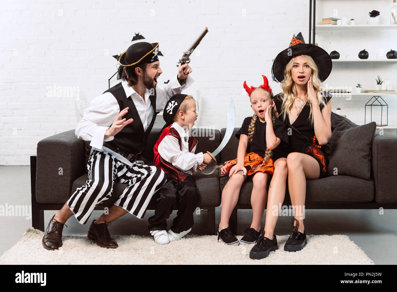 Padre e hijo de piratas disfraces asustando a madre e hija en el sofá en  casa Fotografía de stock - Alamy