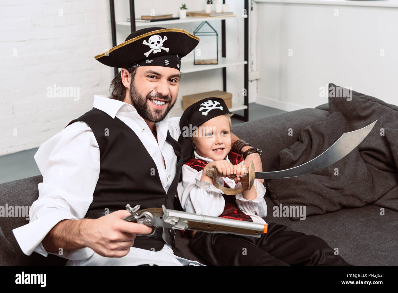 Retrato emocional de padre e hijo de piratas disfraces de Halloween sentado  en un sofá en casa Fotografía de stock - Alamy