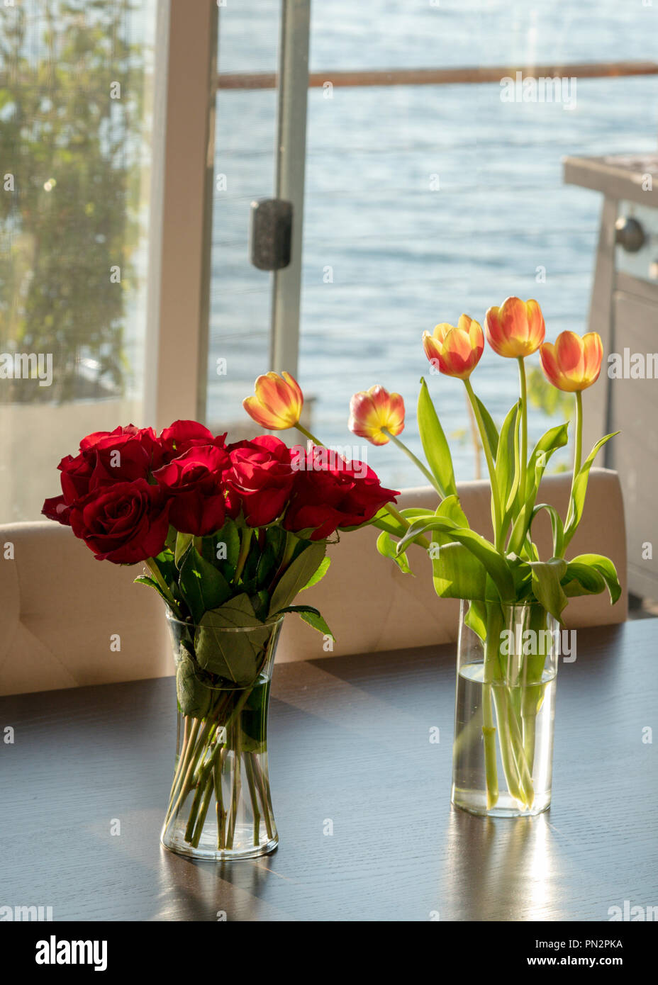 Los Floreros con rosas y tulipanes en la tabla vertical Fotografía de stock  - Alamy