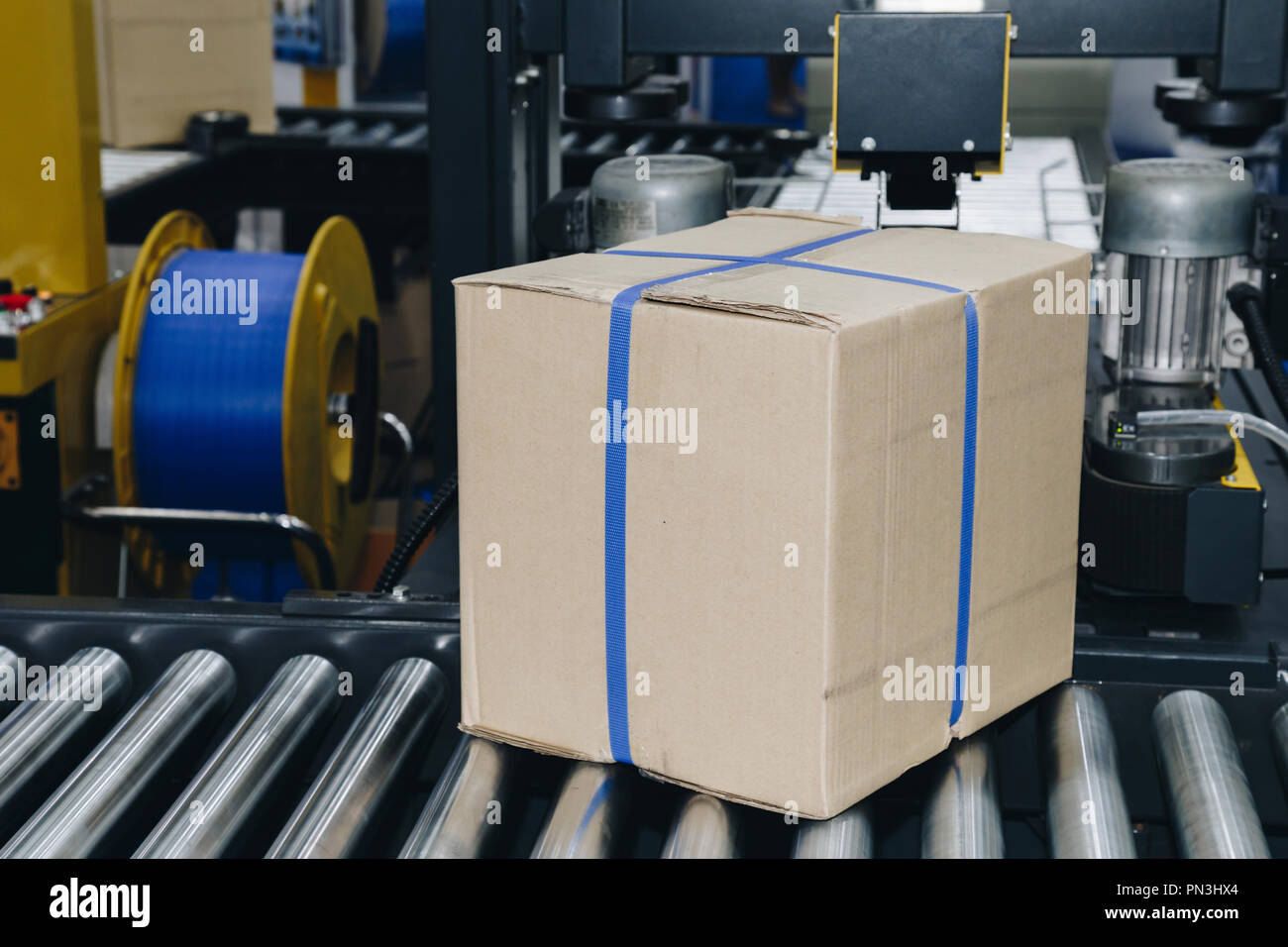 Caja de cartón de embalaje del producto está moviéndose sobre la cinta transportadora de la máquina de embalaje de fábrica listo para su distribución a los Foto de stock