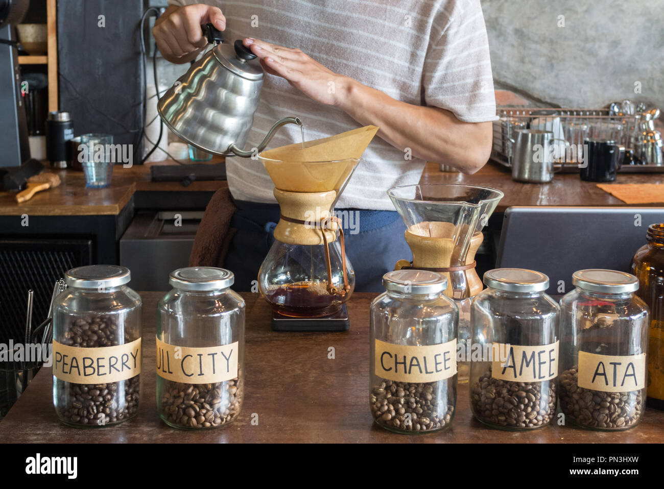 Barista holding pot goteo y verter agua sobre el suelo de granos de café en  el filtro de papel para cafetera de goteo cerveza en el café de la mañana.  El café