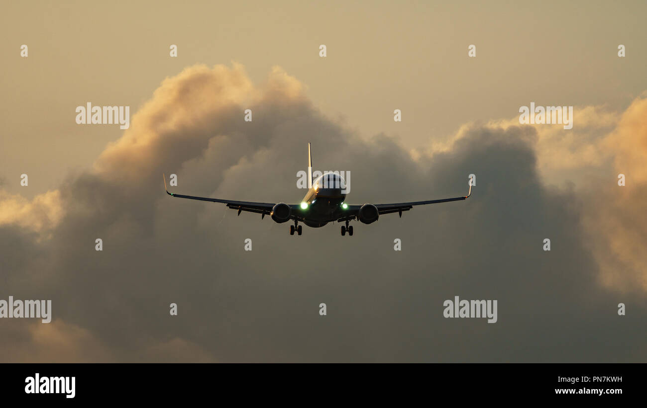 Alto contraste de avión aterrizaba en contra de las nubes Foto de stock