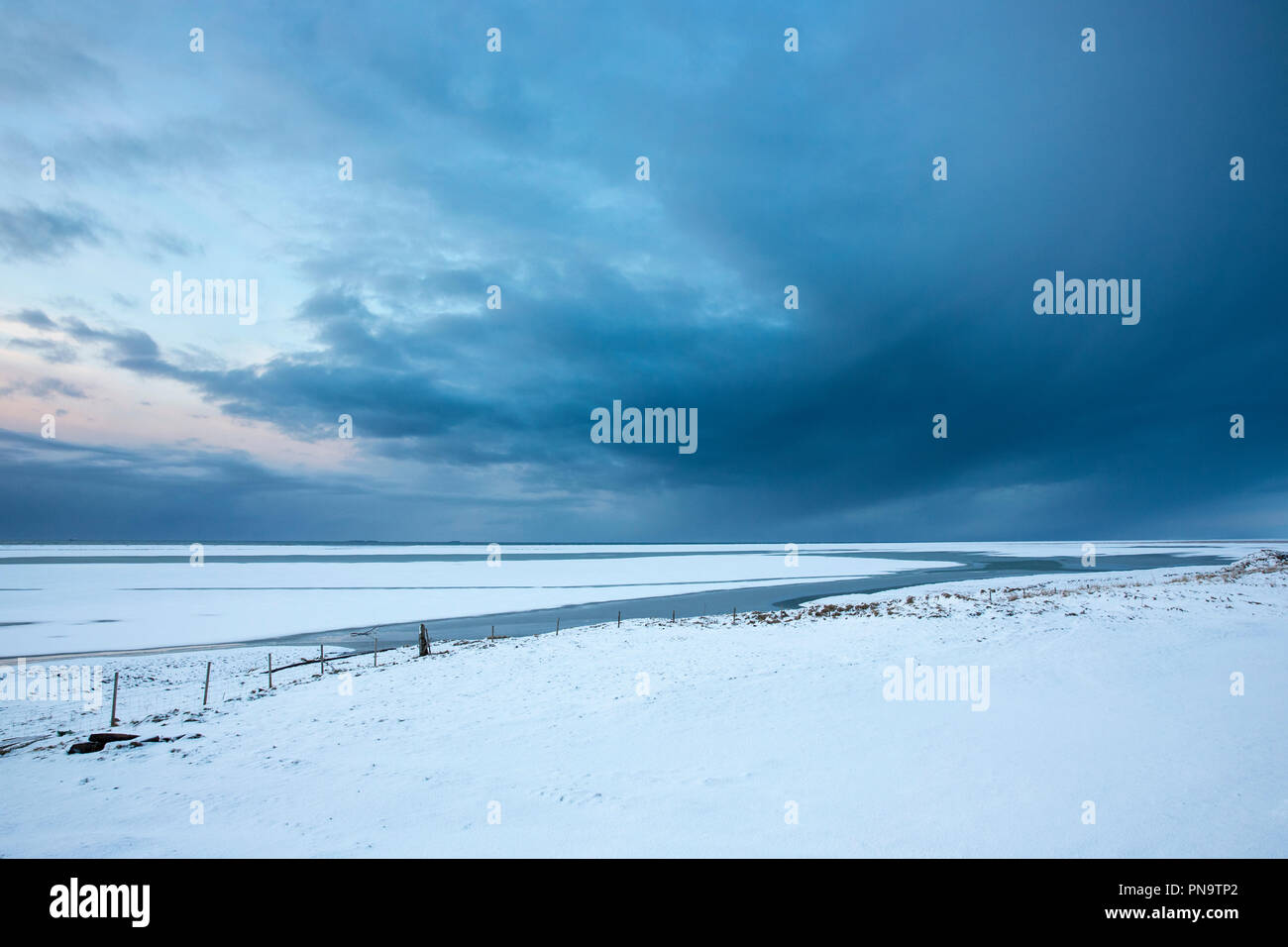 Sol invernal y abultadas nubes sobre Islandia típico paisaje de llanuras cubiertas de nieve hacia el Océano Atlántico cerca de Hofn, sur de Islandia Foto de stock