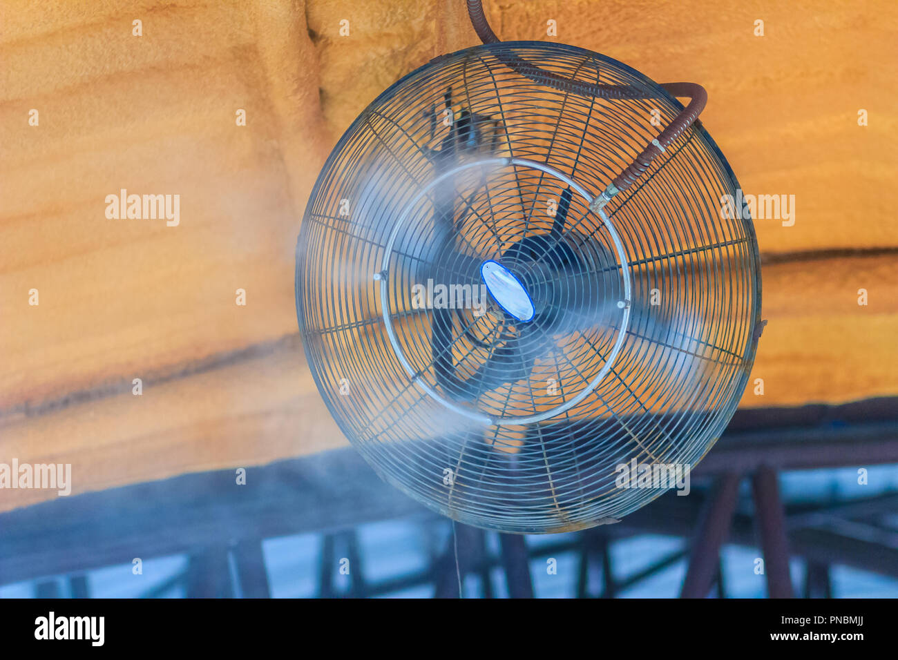 Ventilador de refrigeración de vapor eléctrico en el techo, agua mister  ventilador sopla el agua fresca en el aire para enfriar el área exterior en  un caluroso día de verano Fotografía de