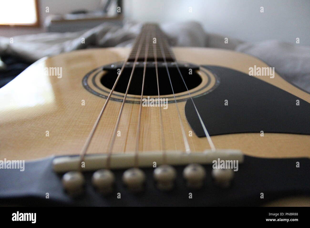 Guitarra acústica acostado en una cama Fotografía de stock - Alamy