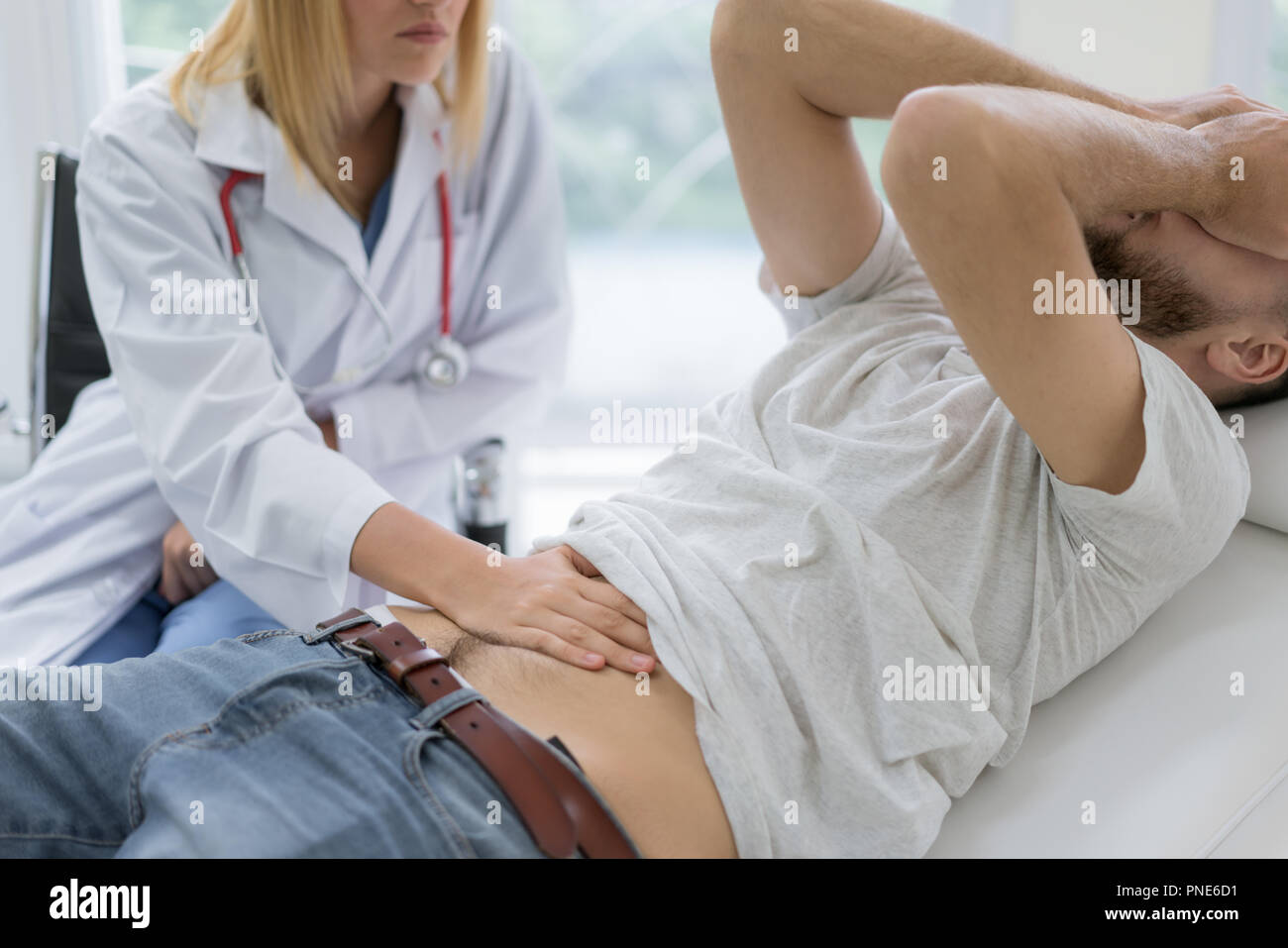 Enfermos y dolor de estómago al hombre que está siendo examinado por el médico. Doctor presionando su estómago del paciente, control del área de dolor Foto de stock