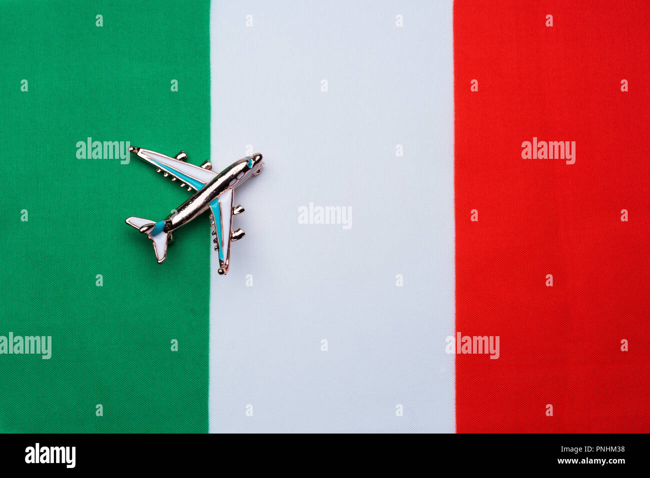 Pabellón de Italia y el avión. El concepto de viaje. Avión de juguete en la bandera de Italia. Foto de stock