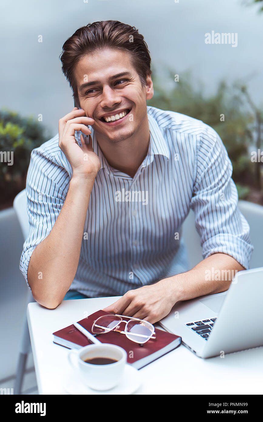 Actitud inteligente. Guapo positivo usando un ordenador portátil y sentado en la cafetería mientras se navega en Internet. Foto de stock