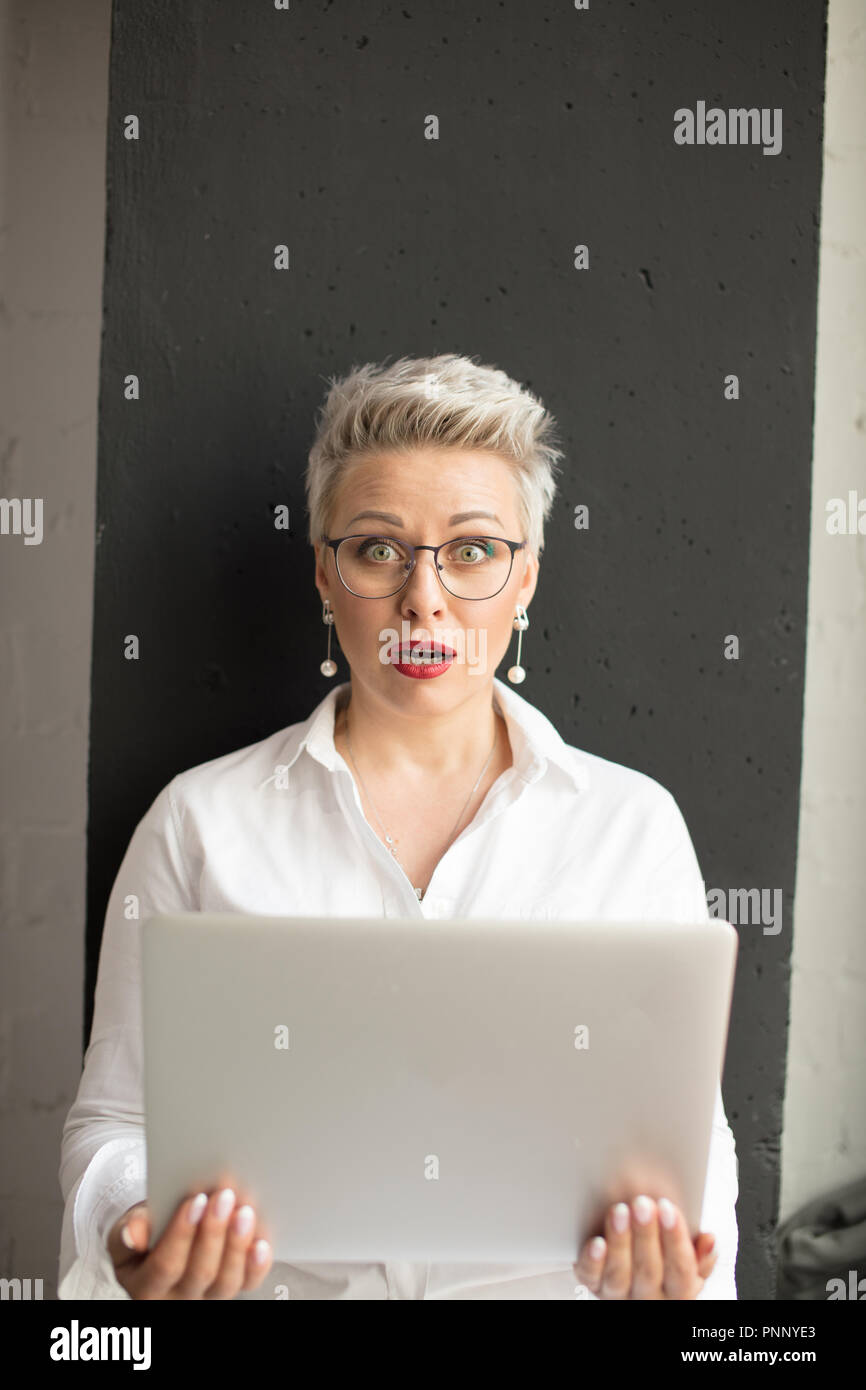 Sorprendido mujer leyendo información inesperada en la laptop con la boca abierta y los ojos saltones Foto de stock