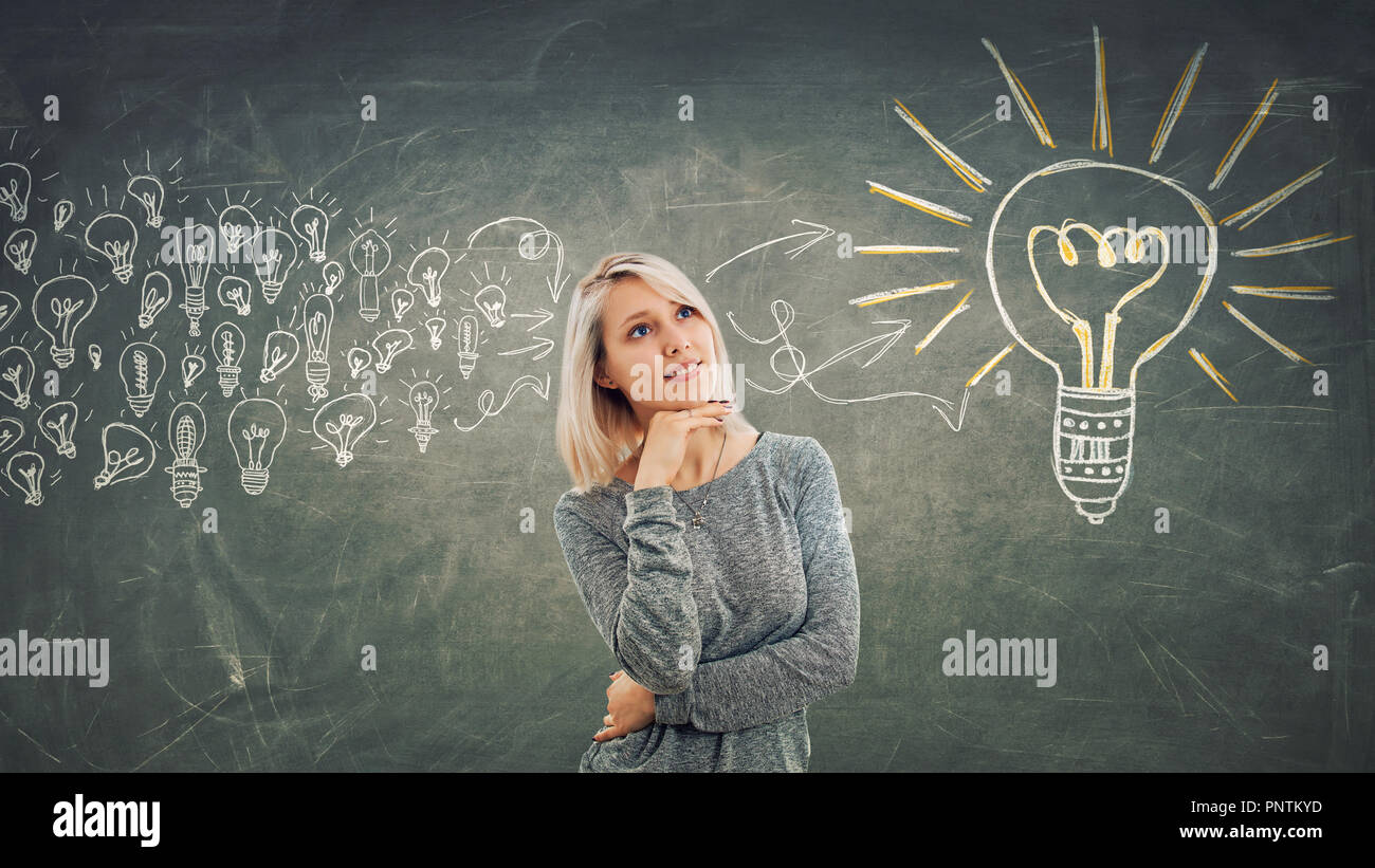 Concepto de negocio como una niña pensativa con la mano bajo el mentón, pensando reunir ideas en un gran foco de luz. Foto de stock