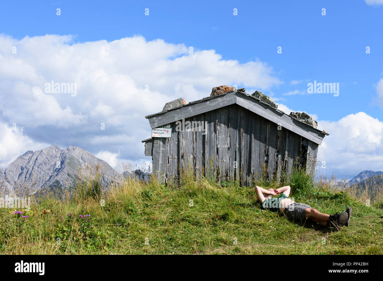 Holzgau: caminante hombre descansando tumbado en la pradera de montaña, hut, Valle de Lechtal, Tirol, Tirol, Austria Foto de stock