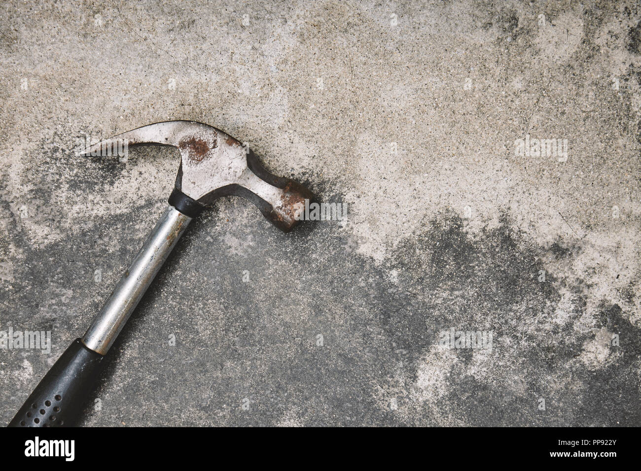 Inicio herramientas de trabajo para reparar, antiguo martillo de acero con óxido en polvo fondo de cemento con espacio de copia Foto de stock