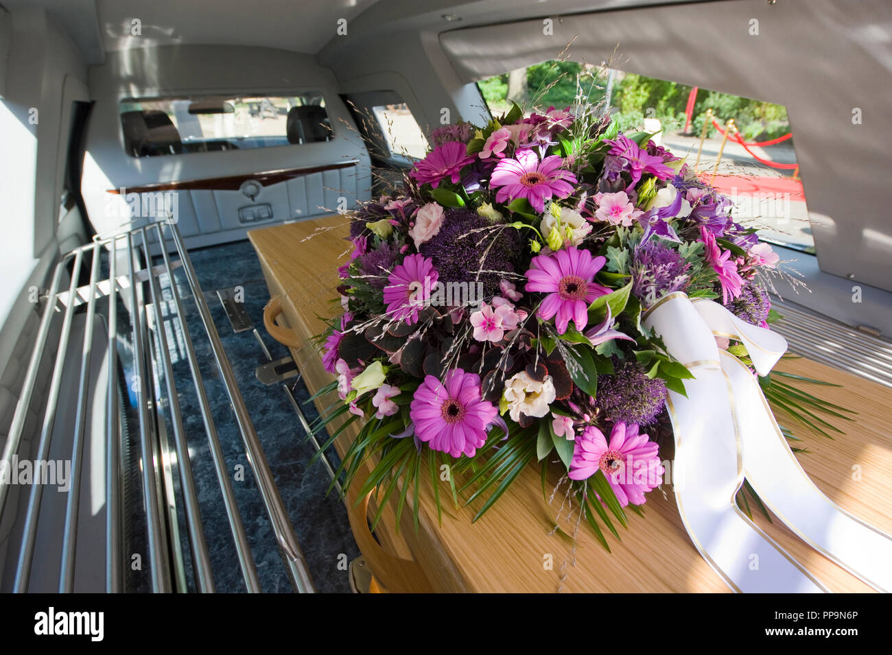 Un ataúd con un arreglo floral en un coche fúnebre Foto de stock