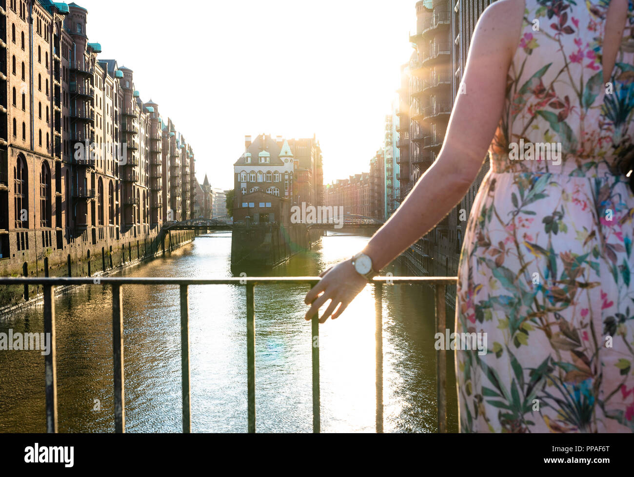 Vista trasera parcial de la mujer en el puente contra edificios históricos y canal Foto de stock