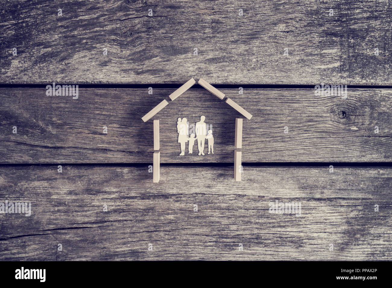 Concepto de bienes muebles o inmuebles con un recorte de una familia con  niños dentro del esquema de una casa, tonos efecto retro Fotografía de  stock - Alamy