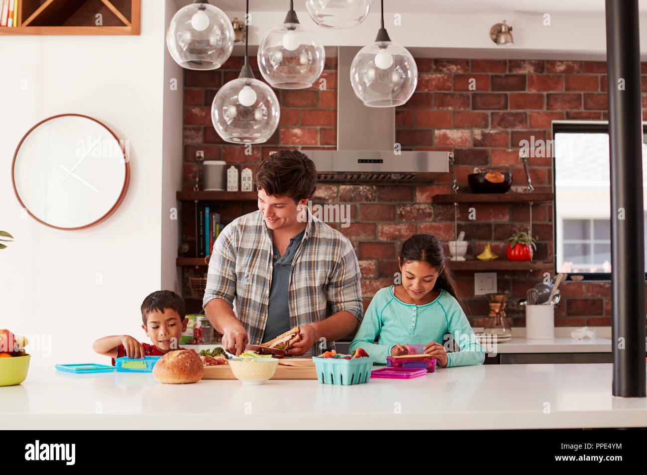Los niños ayudan a padre a hacer los almuerzos escolares en Cocina en casa Foto de stock
