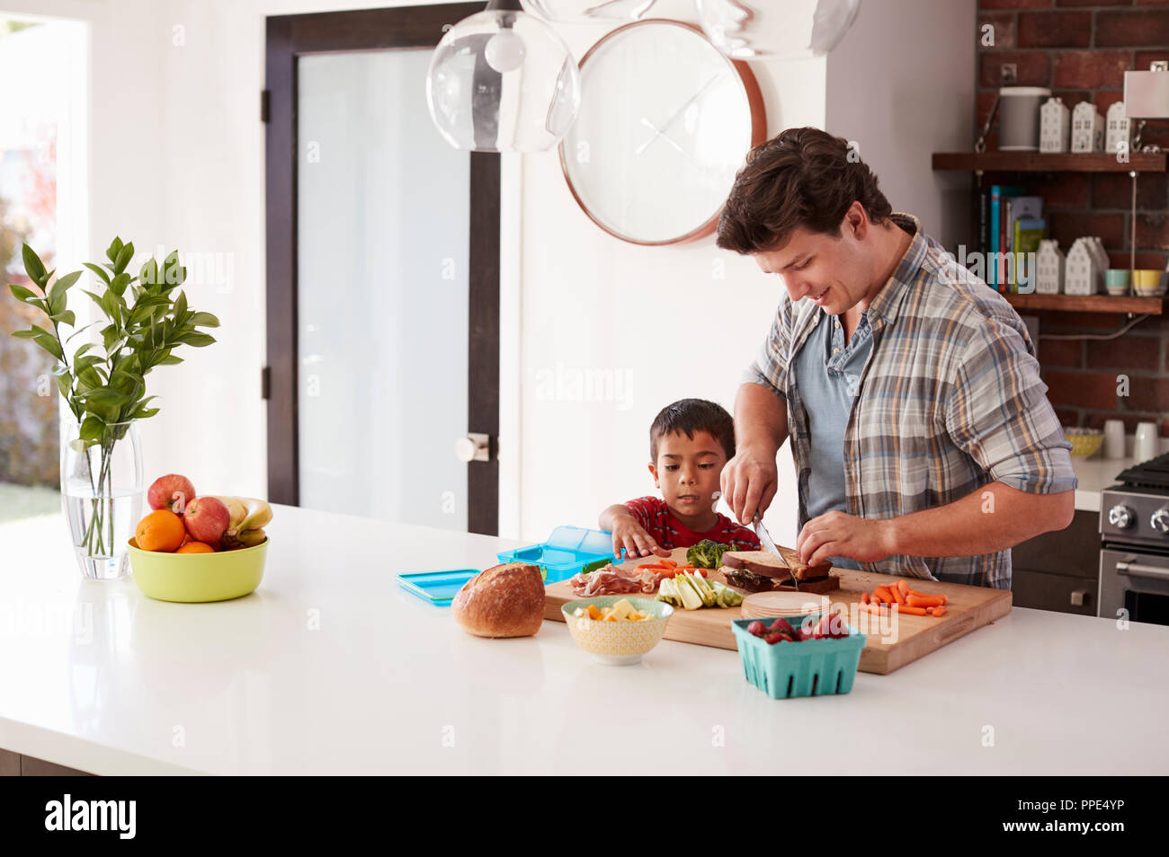 Padre e Hijo haciendo almuerzo escolar en Cocina en casa Foto de stock