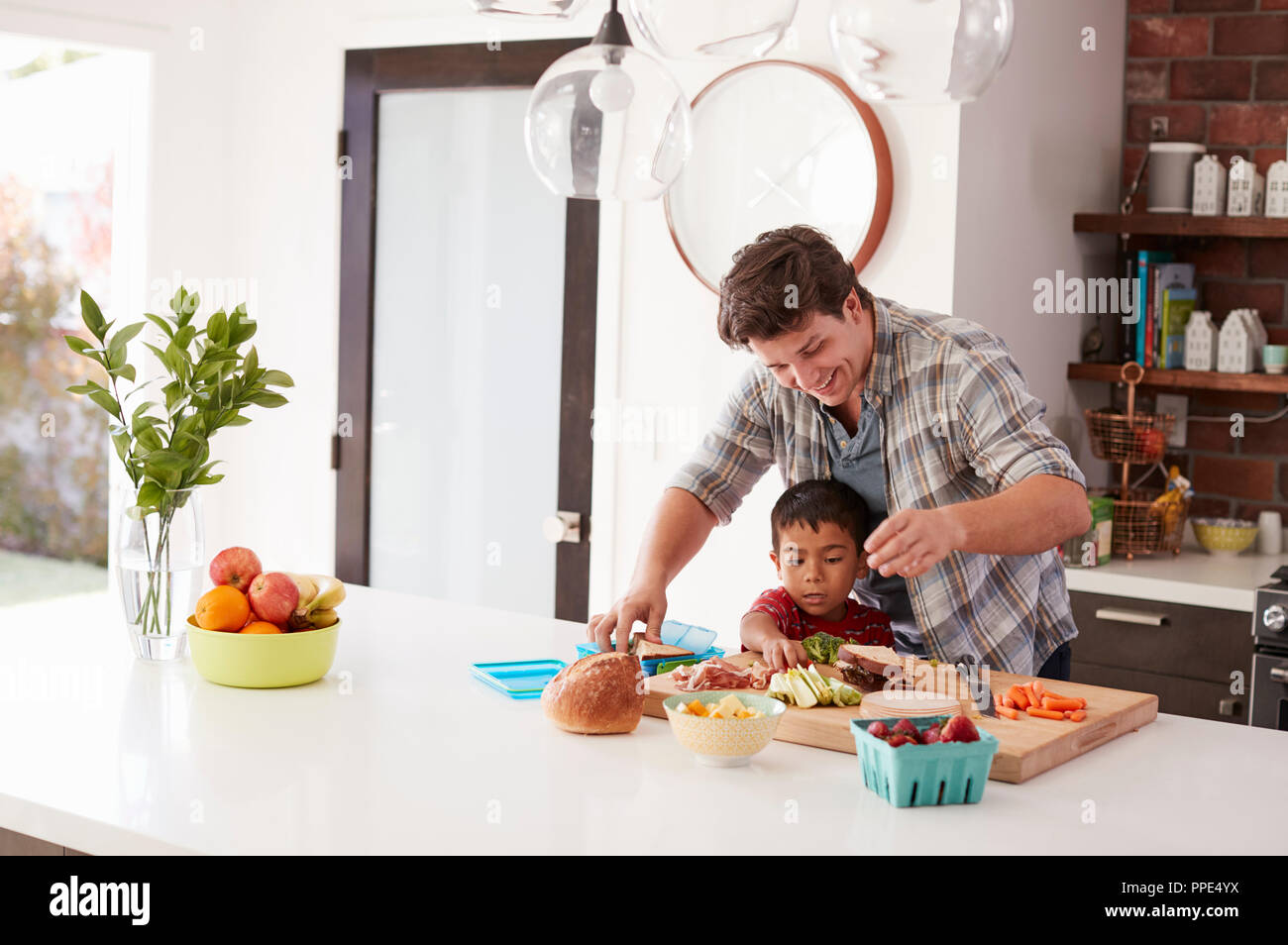 Padre e Hijo haciendo almuerzo escolar en Cocina en casa Foto de stock