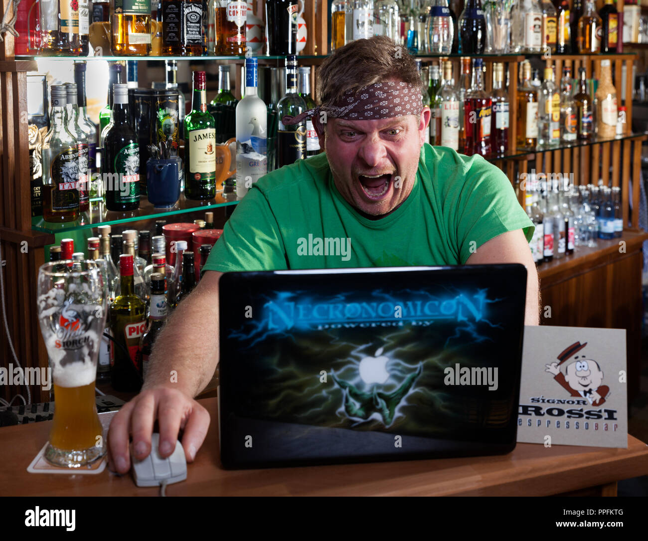 Hombre en internet cafe se ve en el portátil y grita en estado de shock, símbolo imagen para navegar por internet. Alemania Foto de stock