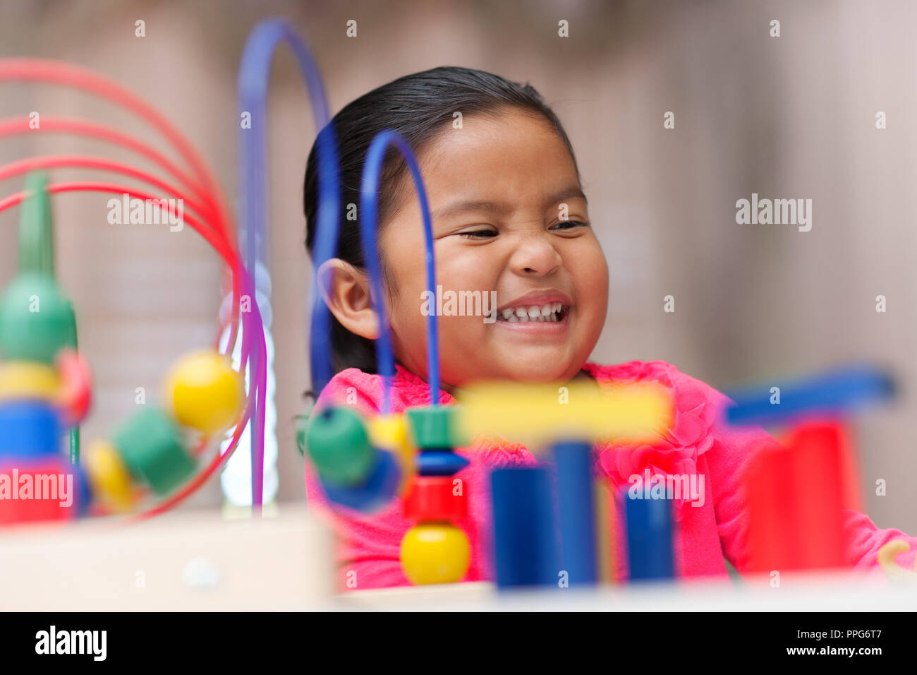 Feliz latino niña jugando con coloridos juguetes educativos para aumentar las habilidades motoras Foto de stock