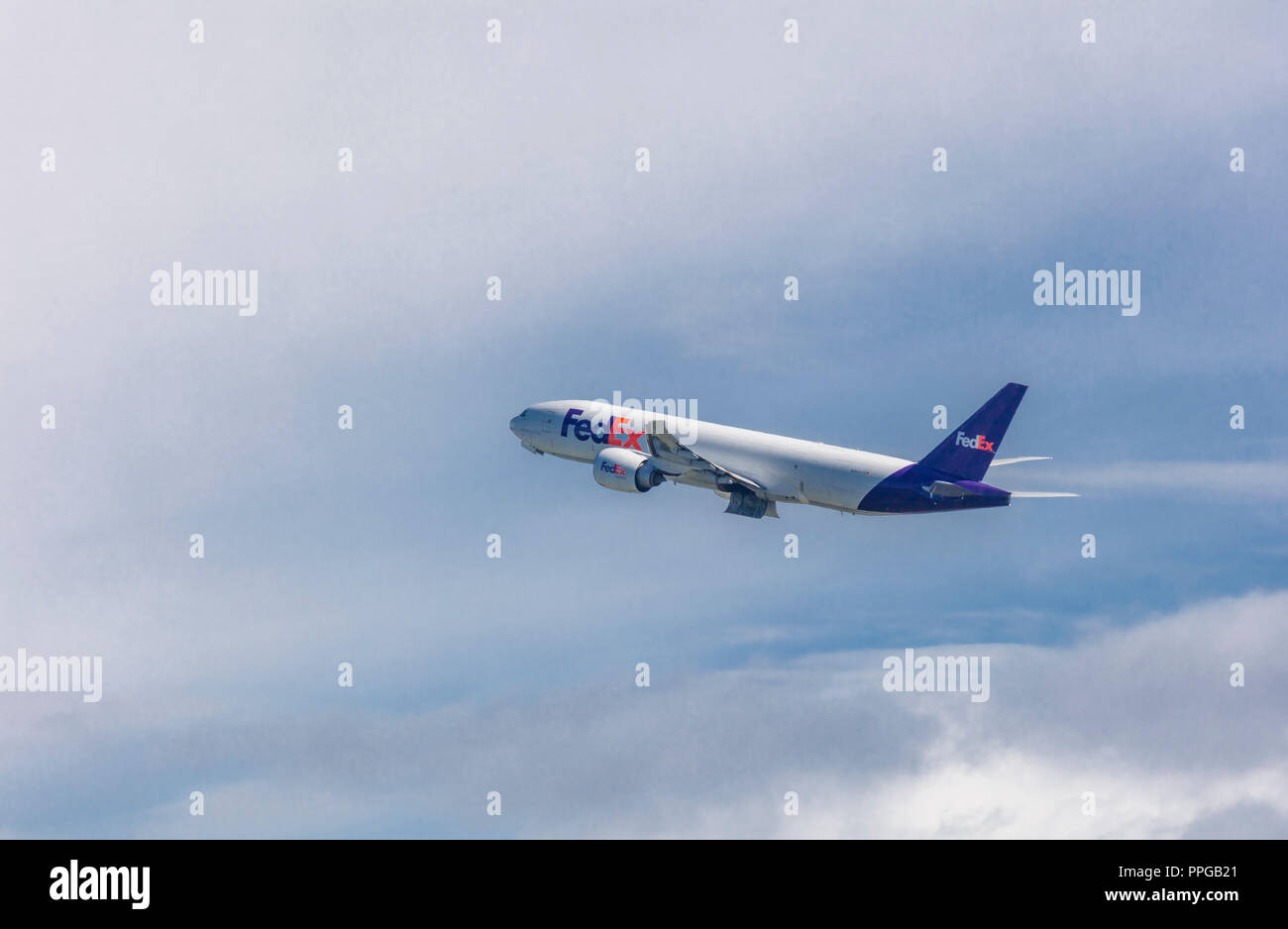 Avión de carga de FedEx despegando en Anchorage, Alaska, en un cielo azul con nubes blancas Foto de stock
