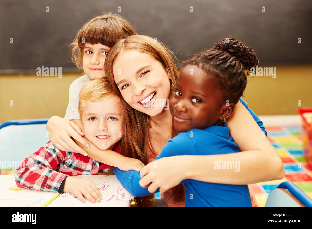 Abracen a sus niños felices childminder en el cuidado infantil Foto de stock