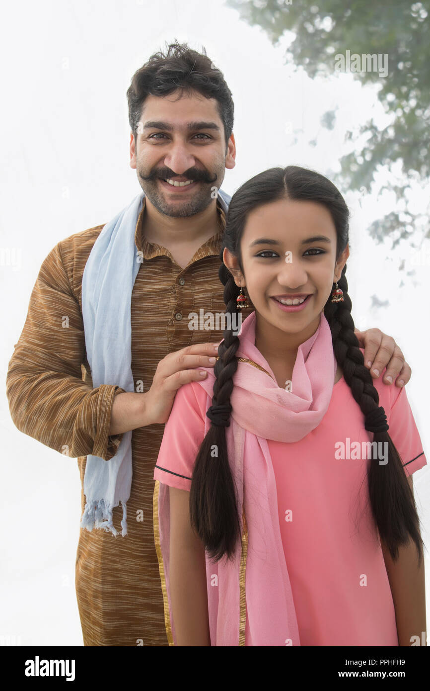 Retrato de un hombre de la aldea de pie sonriente con su hija. Foto de stock