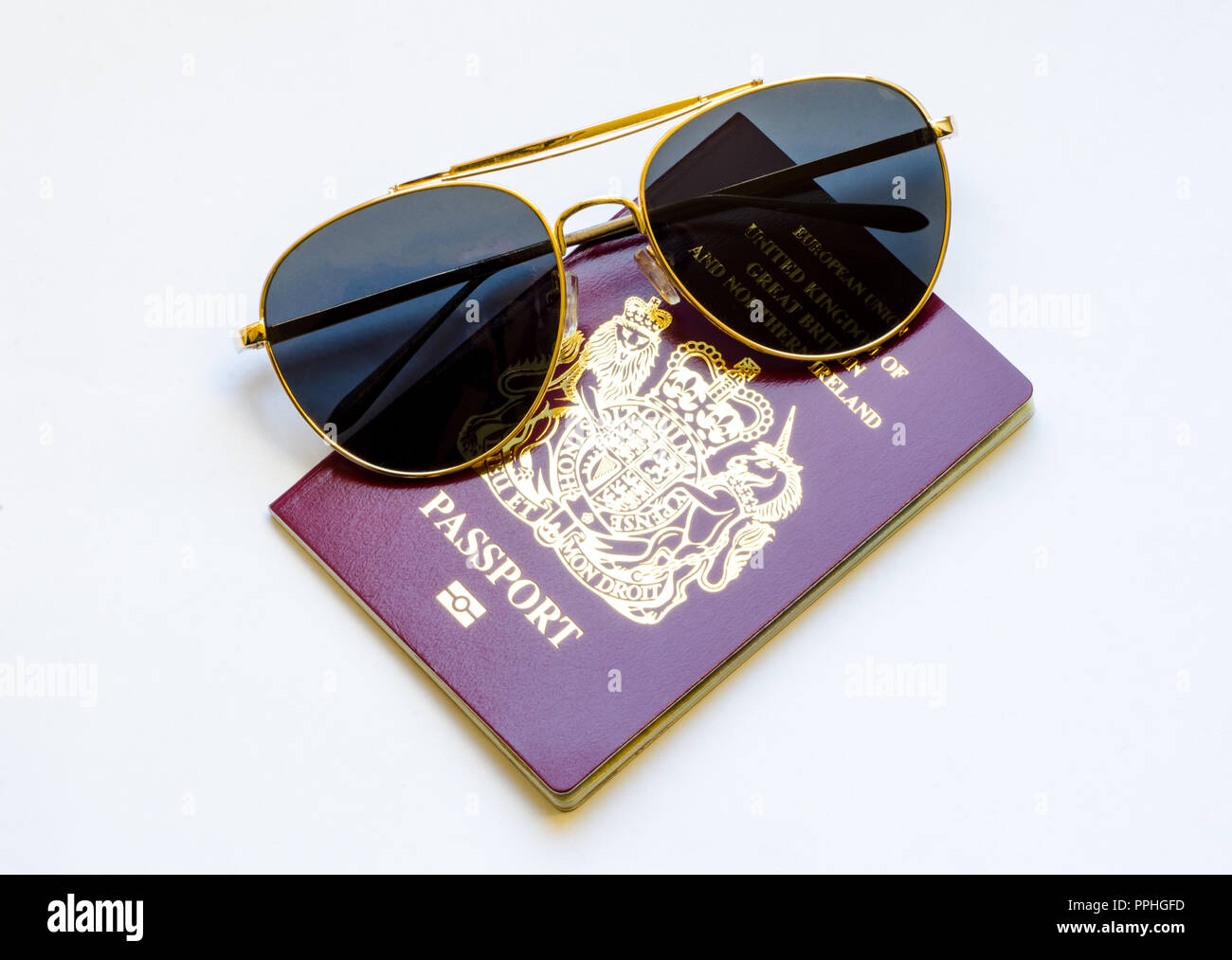 Concepto de Viajes y vacaciones - un rojo, borgoña, British pasaporte europeo y un par de gafas de sol sobre un fondo blanco. Foto de stock