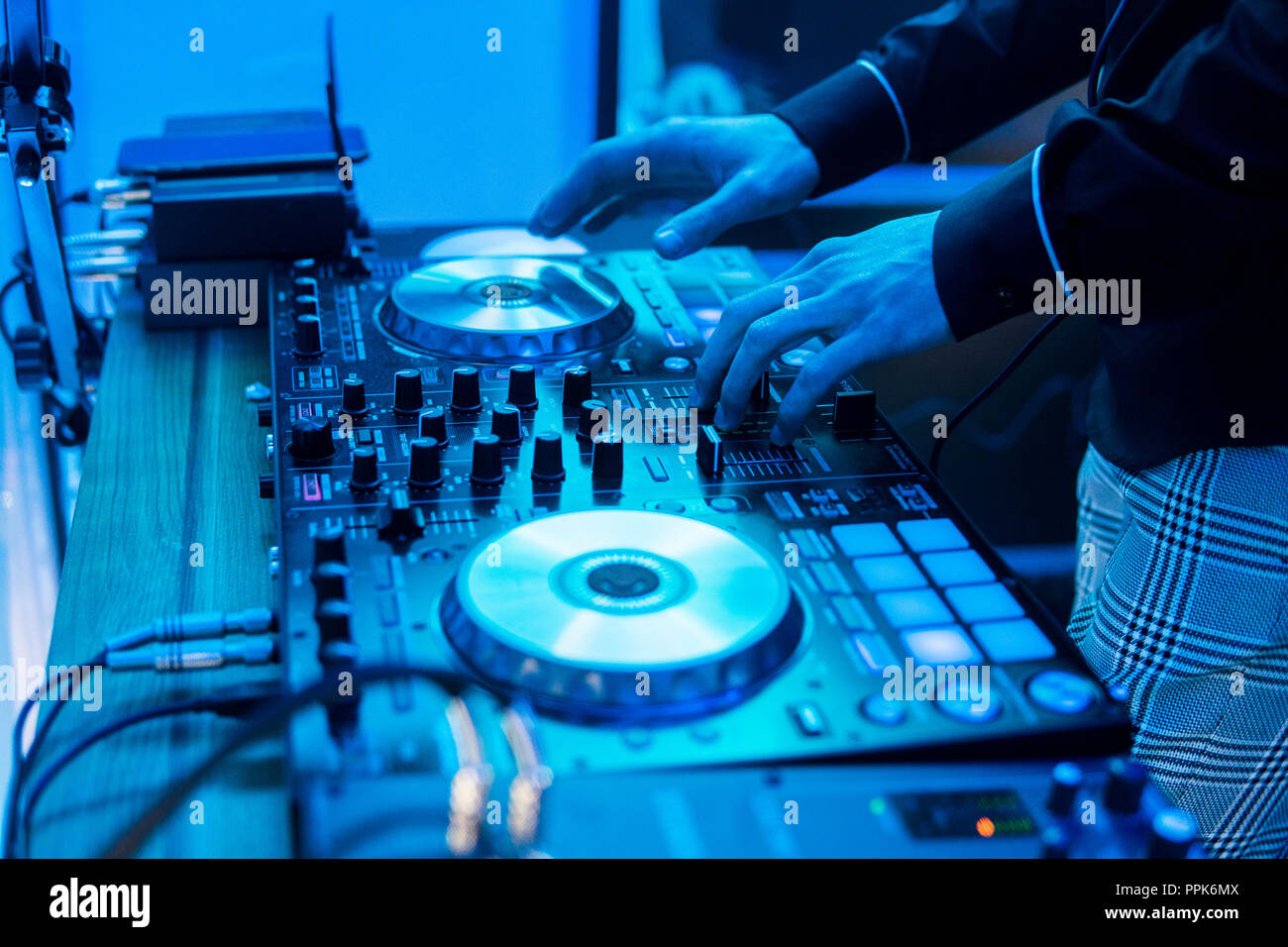 DJ juega y mezclar música en un mezclador digital del controlador. Close-up  DJ controlador midi digital sistema giratorio y ajustable, par,  aluminio-plato giradiscos, fader, mando y control deslizante, botón  Fotografía de stock -