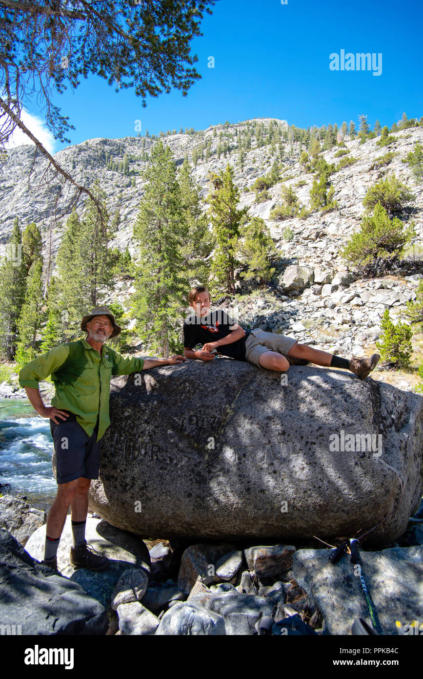 Un padre y un hijo, relajarse en el famoso John Muir Rock, a lo largo