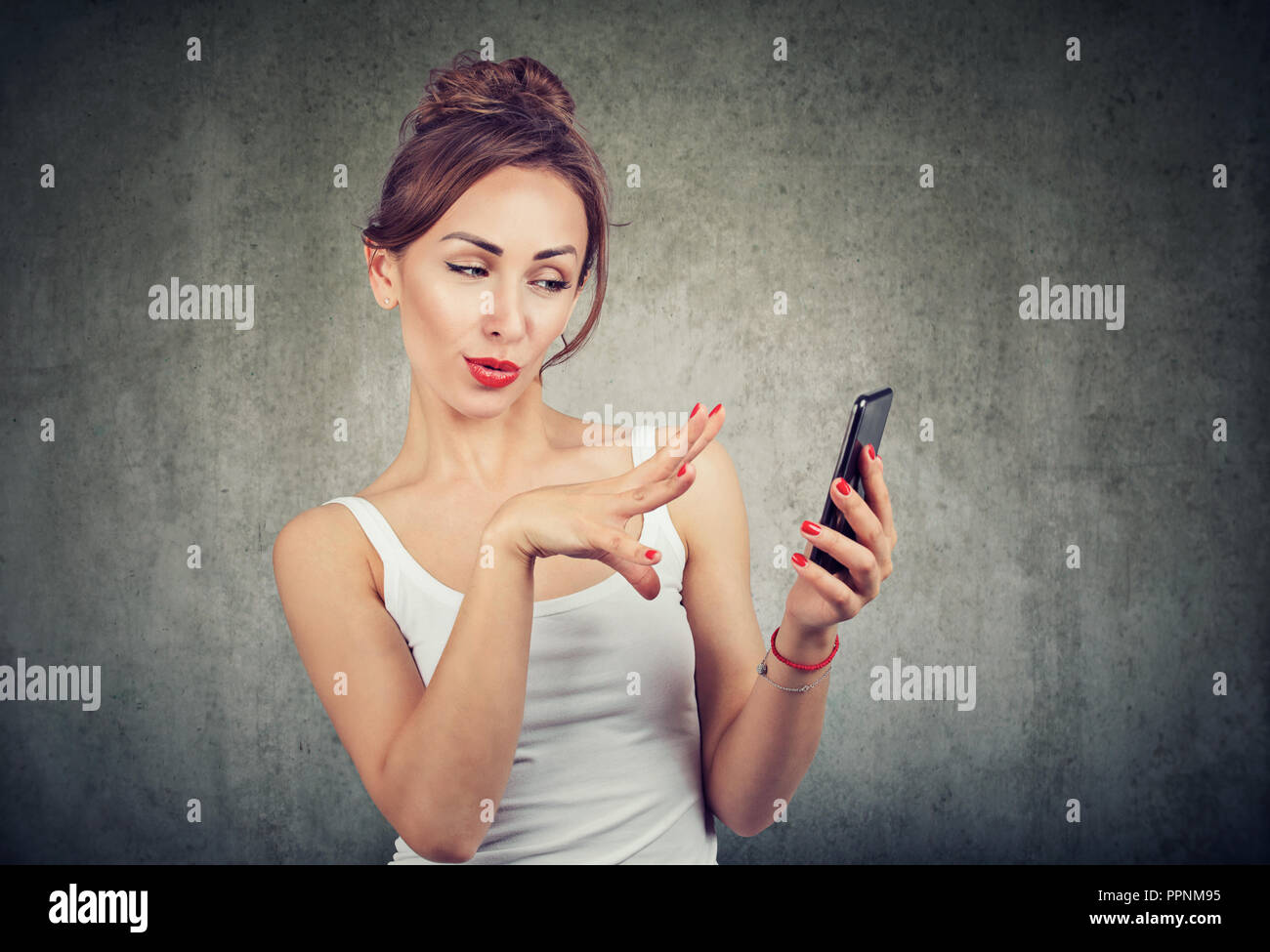 Encantador joven mujer gesticula mientras utiliza el smartphone sin tocar el dispositivo de manipulación Foto de stock