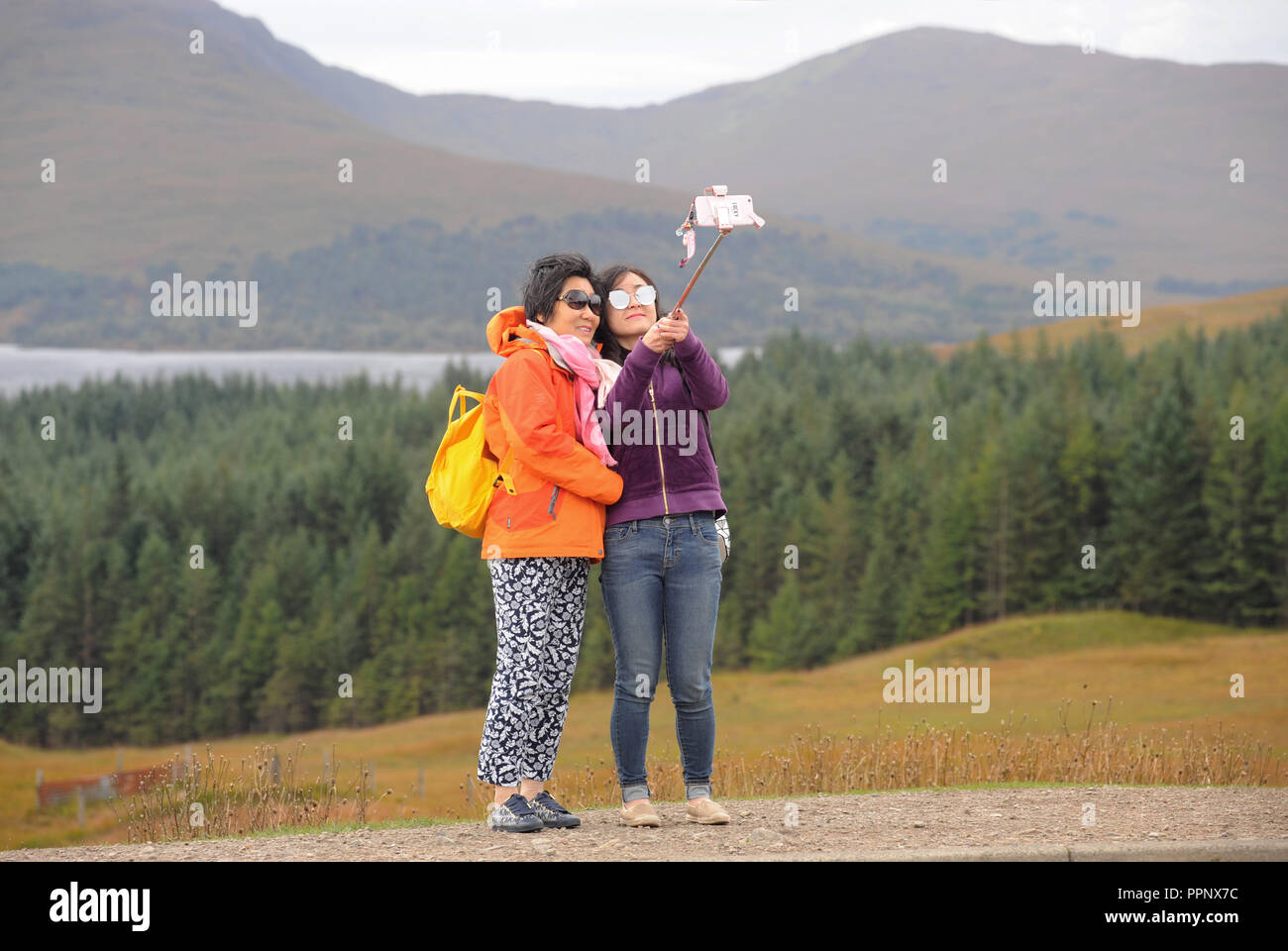 Los turistas japoneses SELFIE tomando fotografías en las Highlands escocesas RE TURISMO AUTOCARES VACACIONES TOURS Mirador vistas escénicas UK Foto de stock