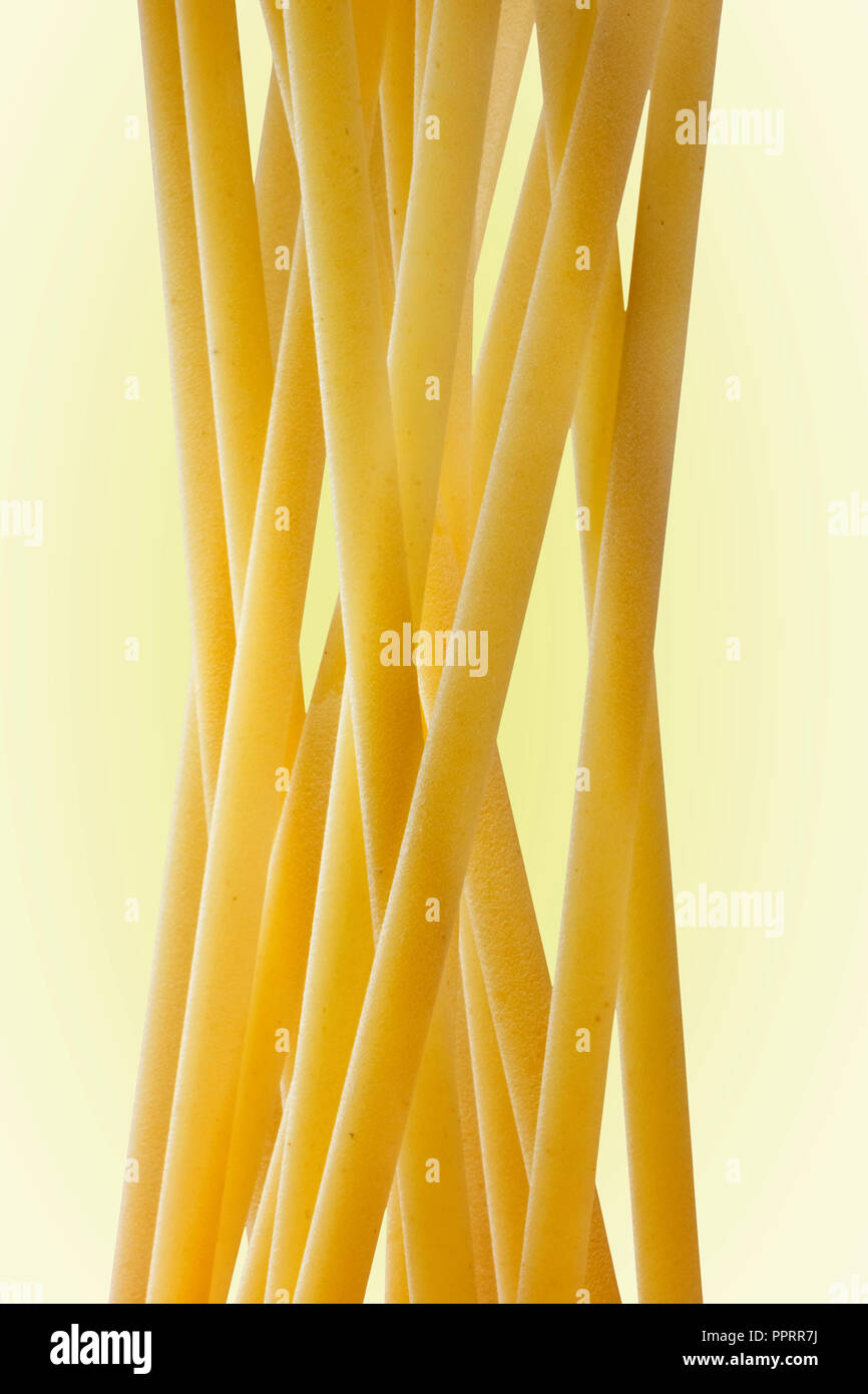 Un grupo de pasta italiana llamado linguine sobre un fondo claro ,plana larga pasta amarillo , efecto abstracto ,composición vertical Foto de stock